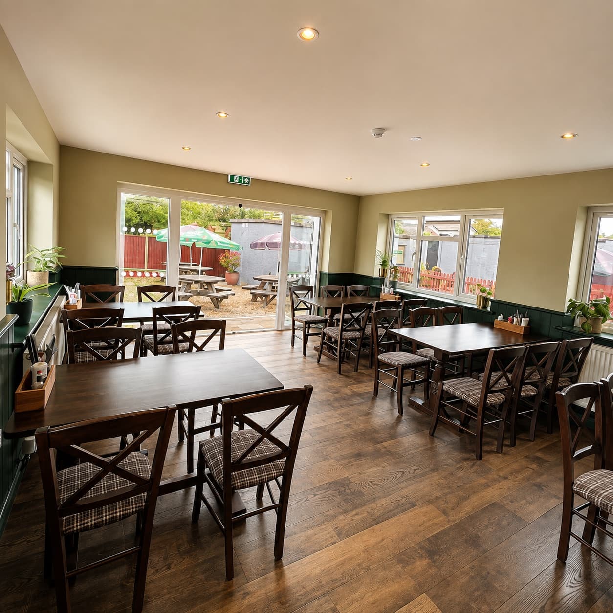 The dining room at The Anchor, with wooden tables, green panelling and French doors onto the garden