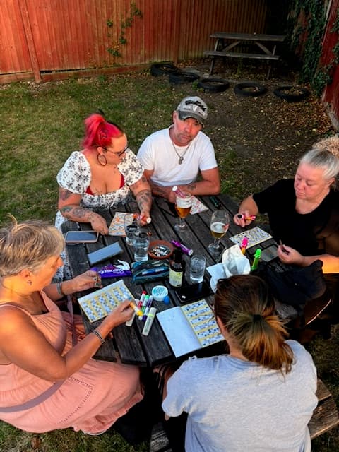 Five players marking their bingo books with daubers at a table at The Anchor