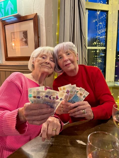 Two winners holding fans of cash after a game of bingo at The Anchor