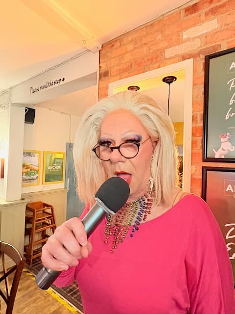 Drag host Nikki Manfadge on the microphone at music bingo at The Anchor