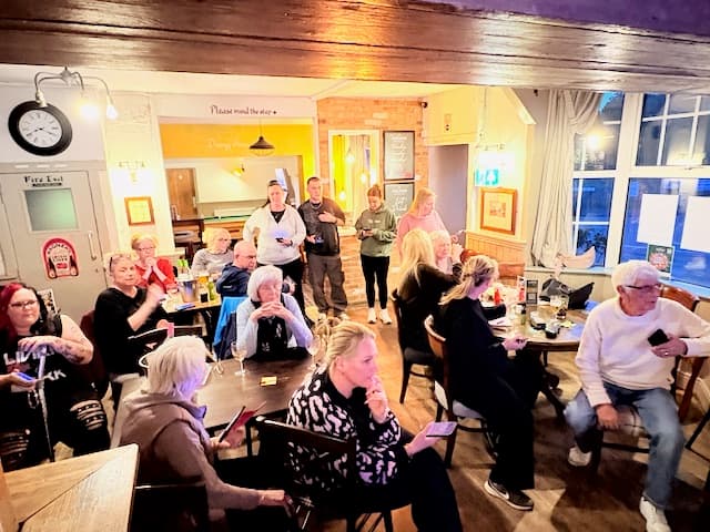 The quizmaster reading a question to a room of seated teams at The Anchor