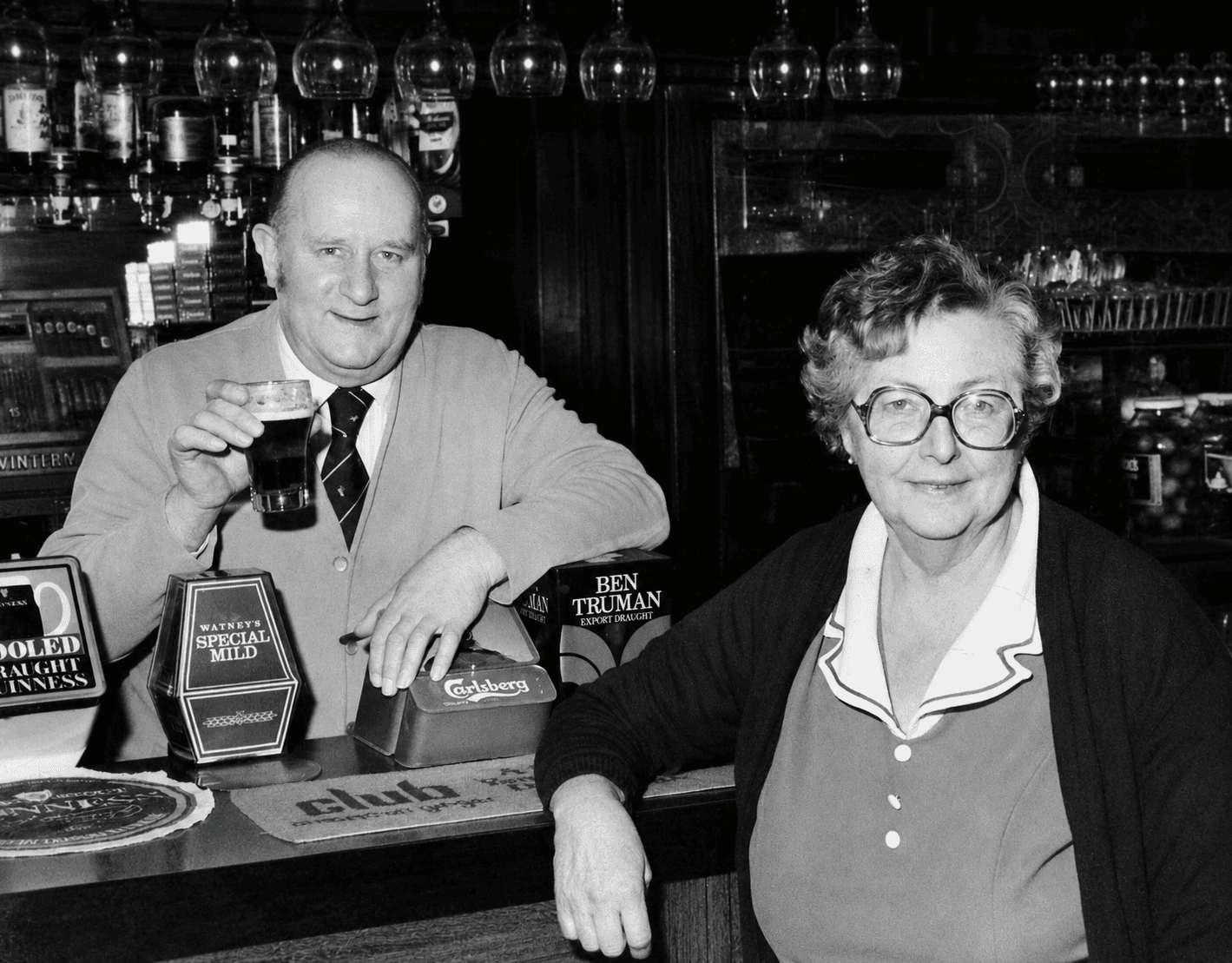 Lal and Charlie Eeles behind the bar at The Anchor, Stanwell Moor, with Watney's Special Mild, Carlsberg and Ben Truman visible on the pumps