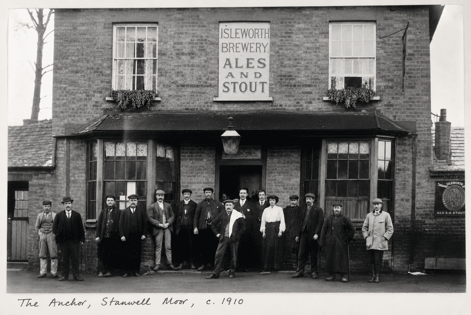 The Anchor, Stanwell Moor, around 1910, the brick pub with Isleworth Brewery 'Ales and Stout' signage and a group of villagers gathered outside the entrance