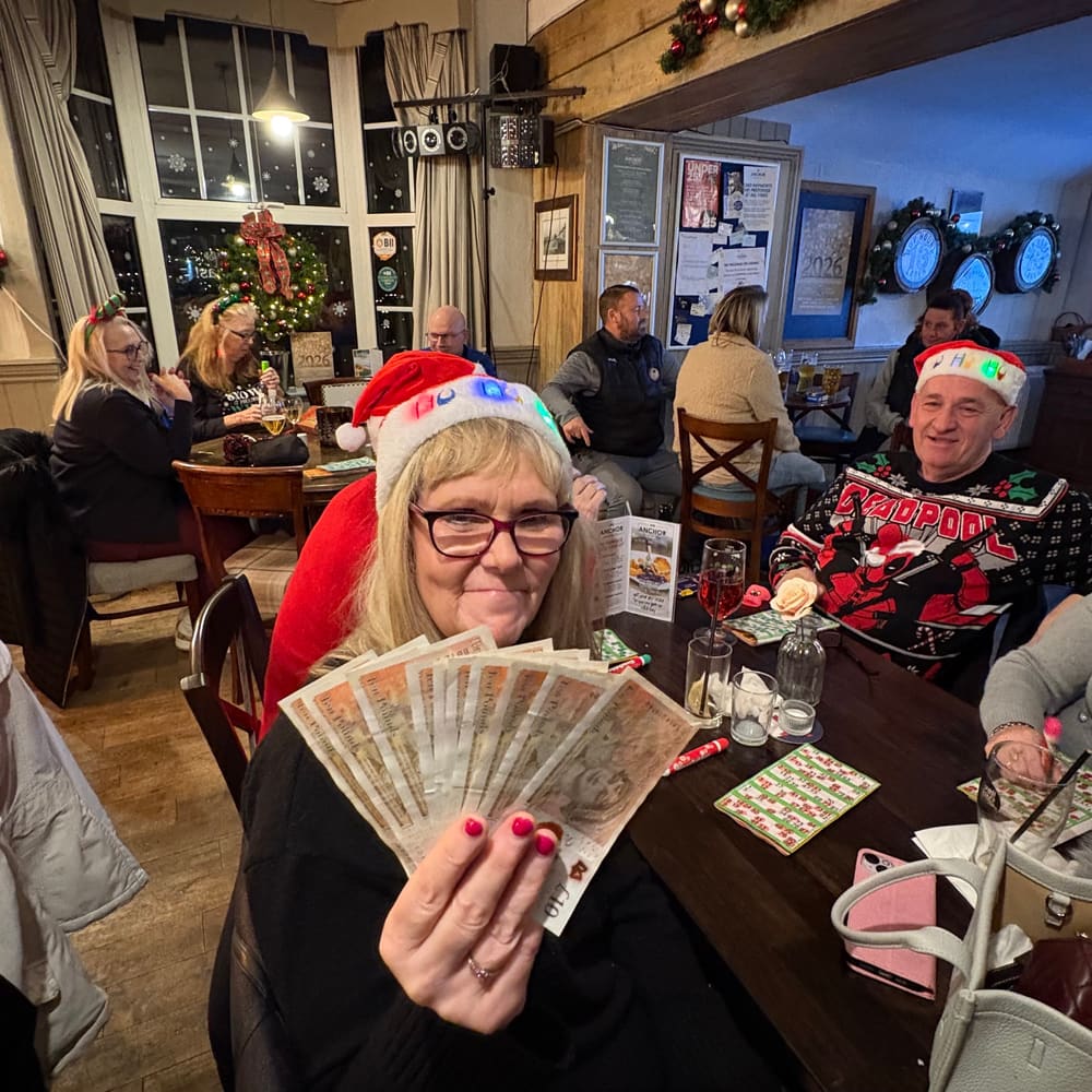Bingo winner smiling and holding a cash prize at The Anchor
