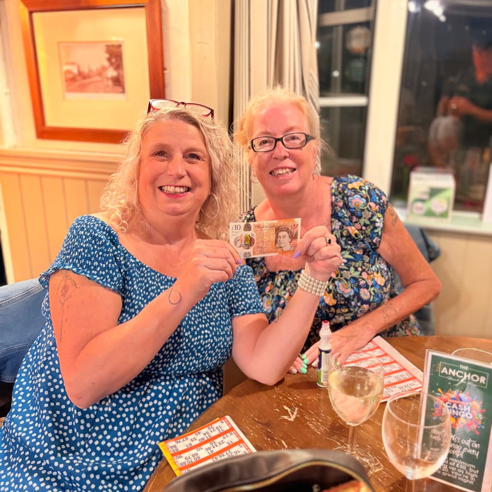 Guest holding a £10 note during a community bingo night at The Anchor